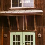 A rustic wooden building facade with green doors and windows, capturing vintage charm.