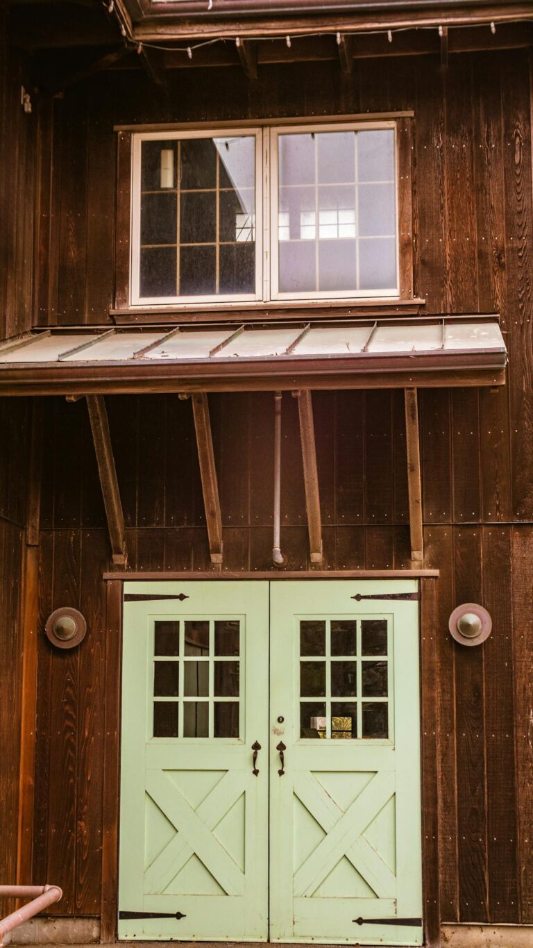 A rustic wooden building facade with green doors and windows, capturing vintage charm.