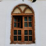 Photograph of an arched wooden window with intricate design in Gujrat, India.
