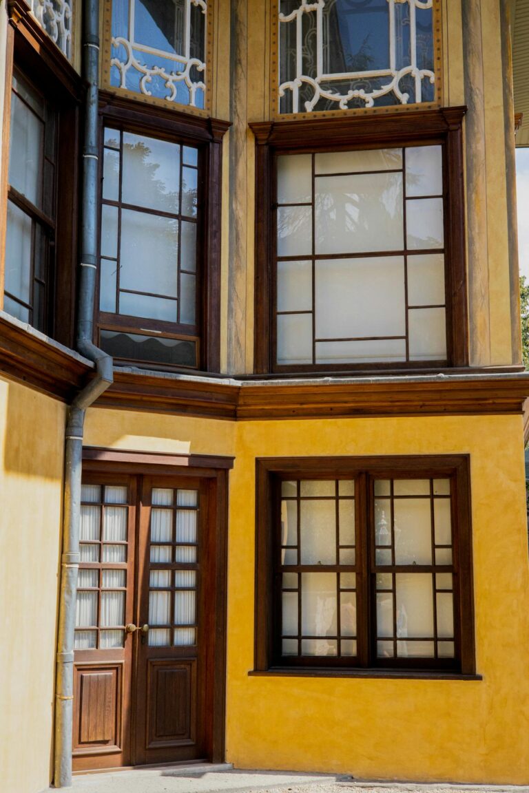 Stylish yellow building facade with wooden framed windows and doors, capturing an elegant architectural detail.